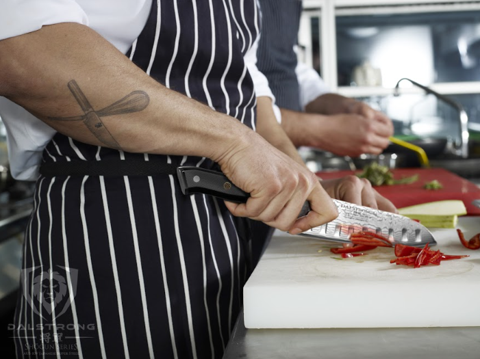 Chef using sharp knife to cut through body of Red Snapper