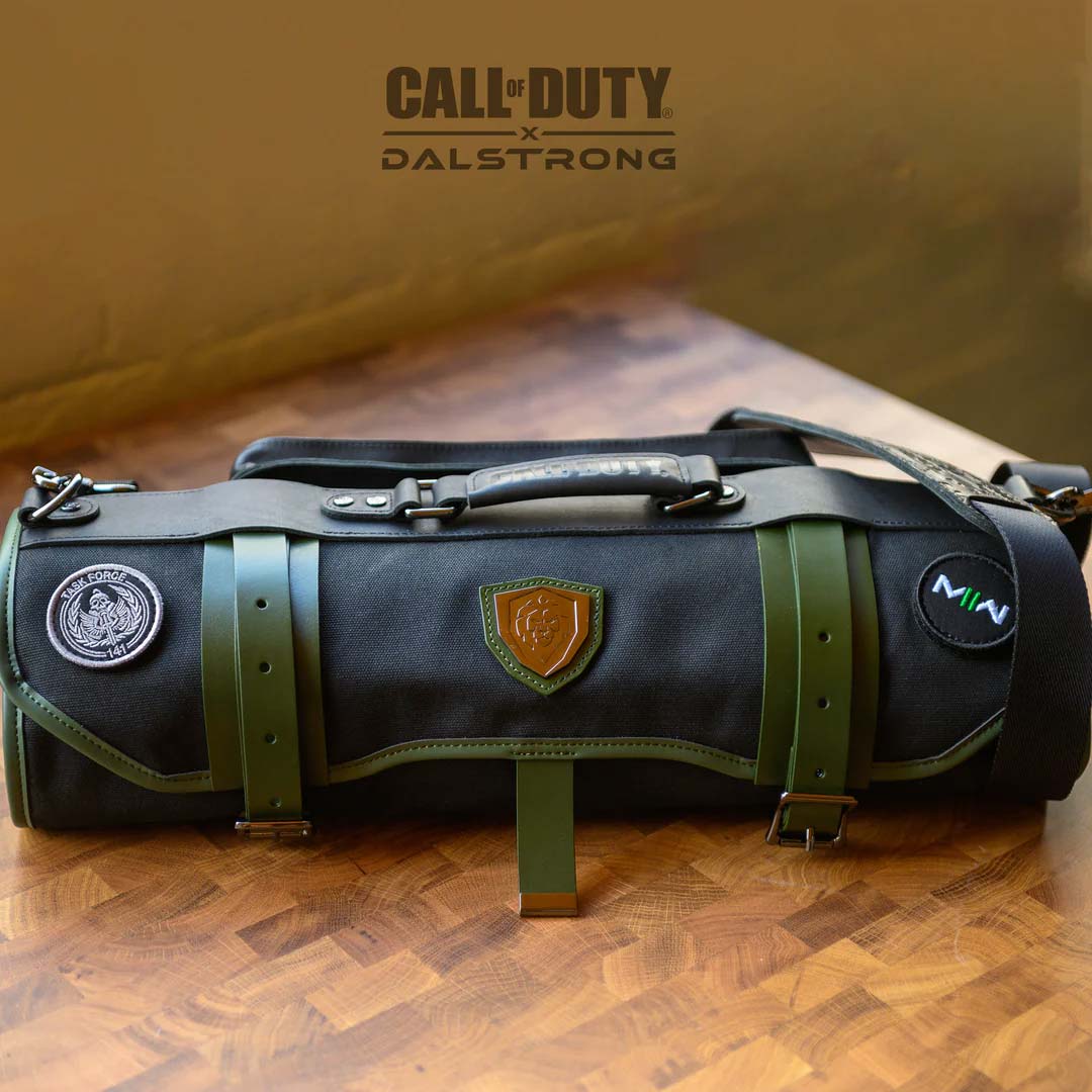 Dalstrong exclusive collector roll call of duty edition black waxed canvas knife roll on a cutting board.