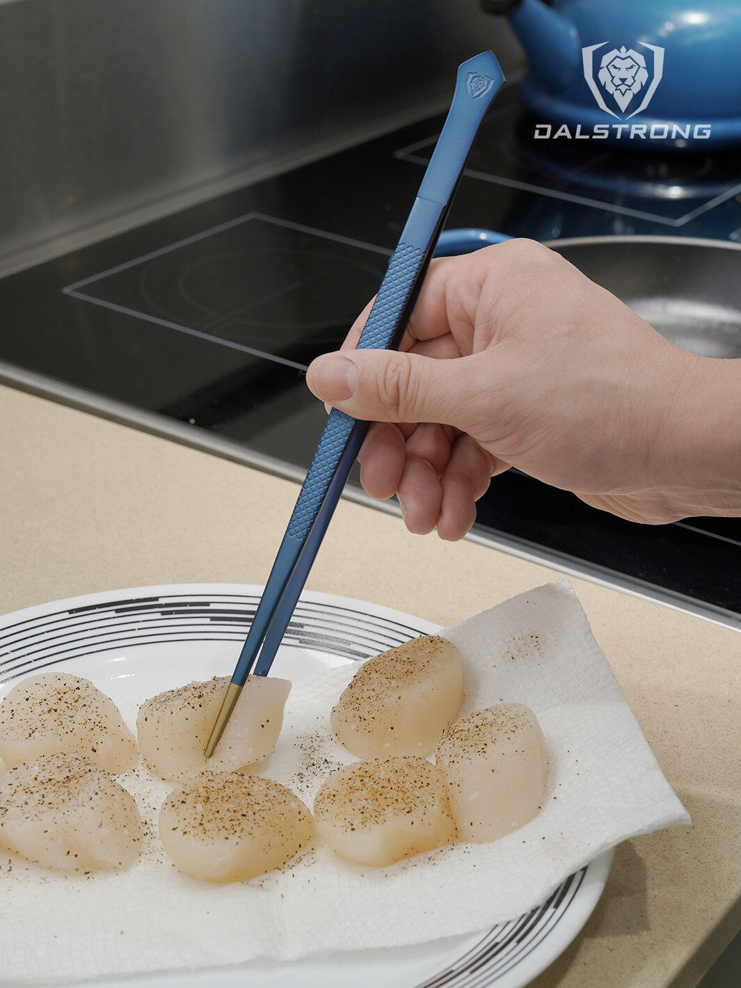 Dalstrong professional 10 inch plating tweezers with scallops on a plate.