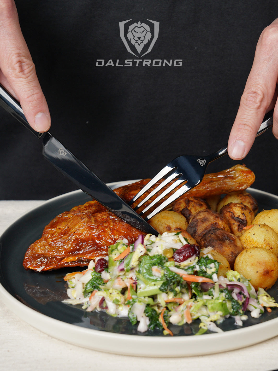 Dalstrong 20 piece flatware cutlery set black stainless steel service of 4 with a cooked chicken and potato in a plate.