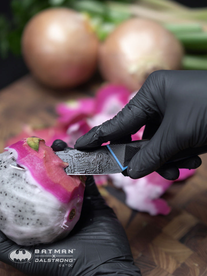 Dalstrong shadow black series 2 piece knife set batman edition with a peeled dragon fruit.