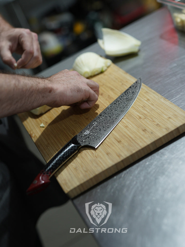 Dalstrong scorpion series 9.5 inch chef knife with red handle and onions on a cutting board.