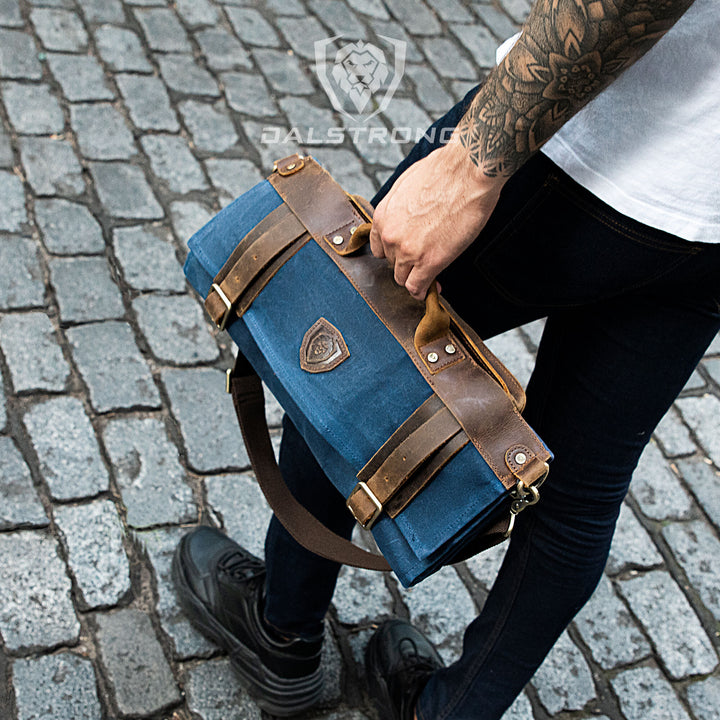 A man with black pants is holding the Dalstrong 12oz heavy-duty canvas and leather blue nomad knife roll.