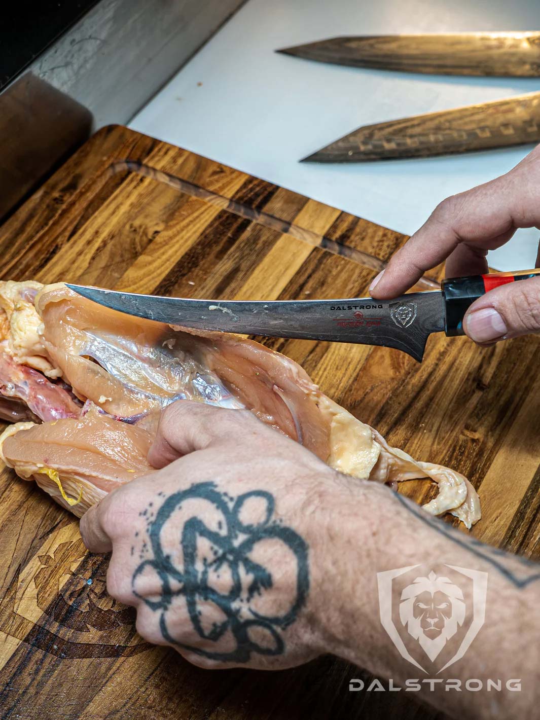 Dalstrong firestorm alpa series 6 inch curved boning knife deboning a chicken meat on a cutting board.