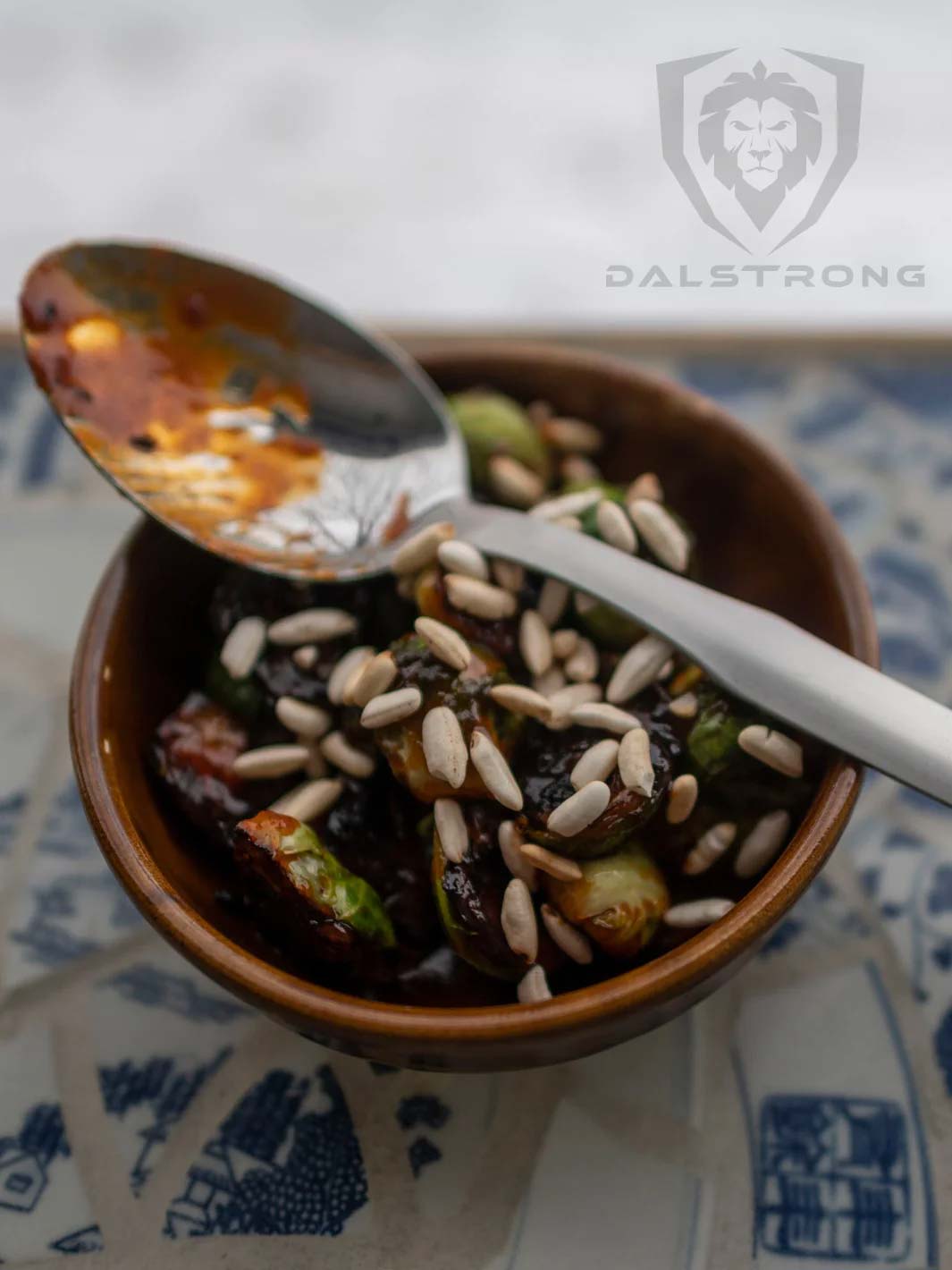 Dalstrong professional chef tasting and plating spoon on top of a bowl filled with cooked brussel sprouts.