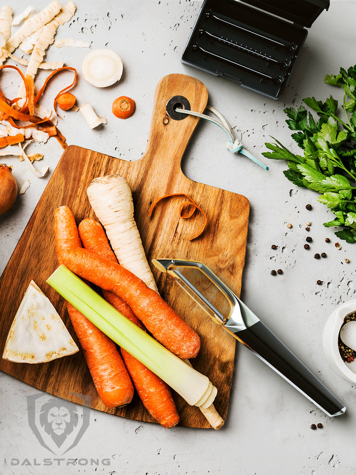 Dalstrong swivel straight peeler with 3 blades in a case with carrots on a cutting board.