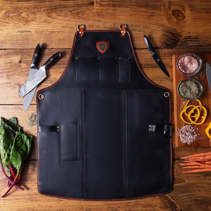 Dalstrong the culinary commander professional chef's kitchen apron with knives at the side on a table.