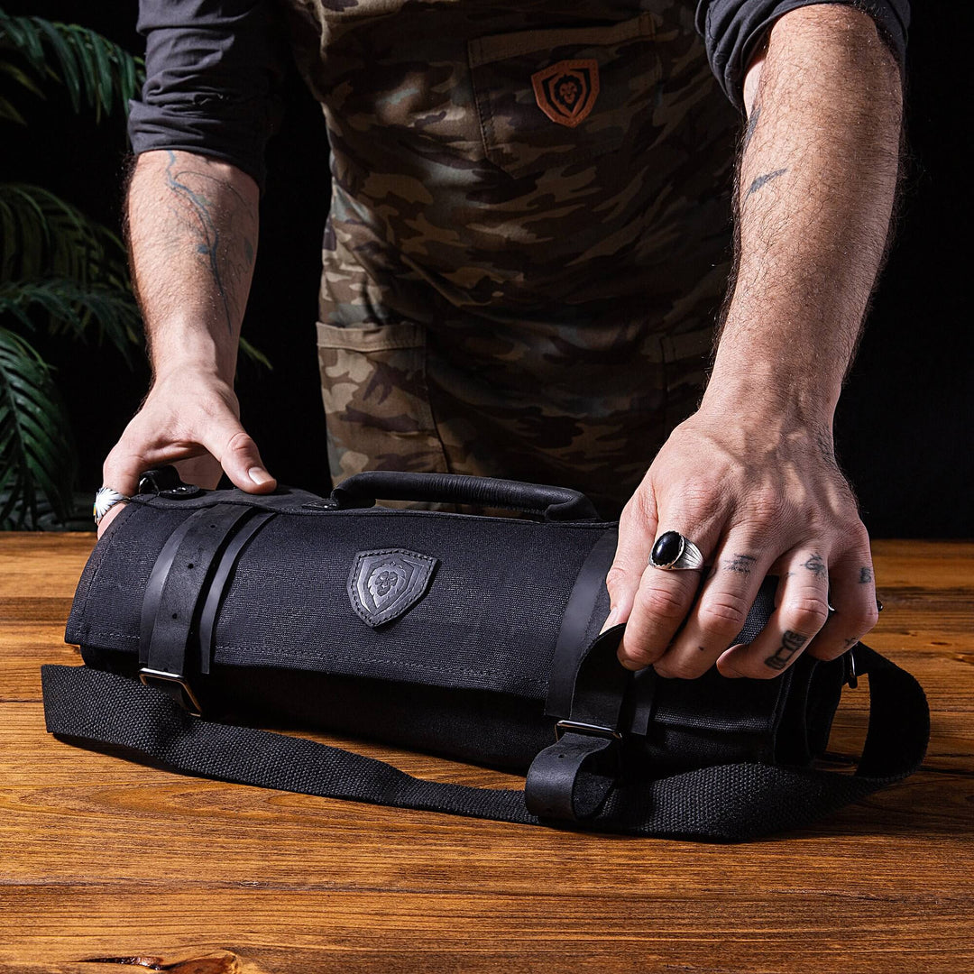 Dalstrong 12oz heavy-duty canvas and leather night master black nomad knife roll on top of a table.
