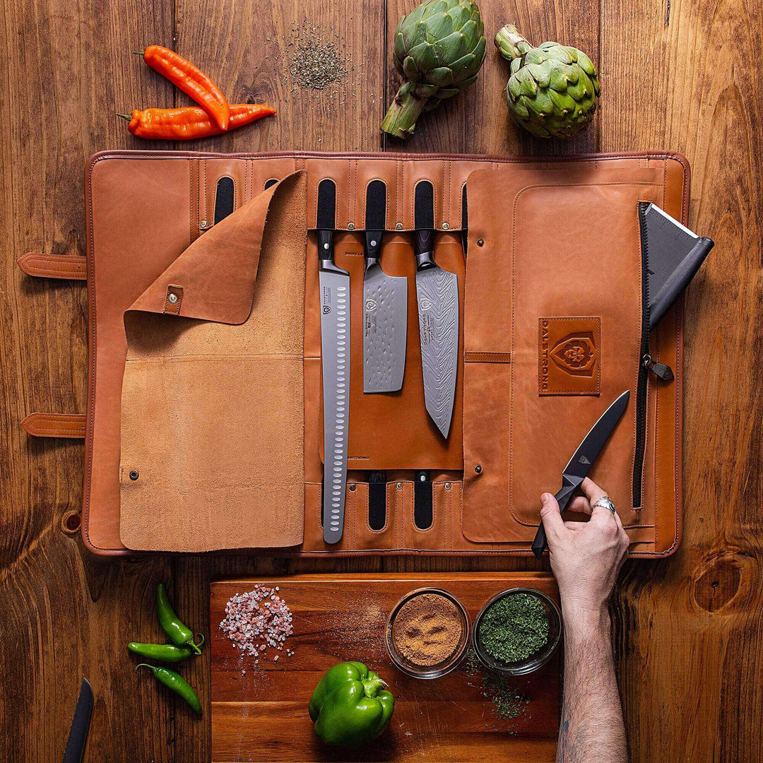 Dalstrong california brown full grain leather vagabond knife roll surrounded by chilli and bell pepper.