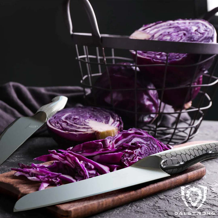 Dalstrong frost fire series 7 inch santoku knife with white handle and chopped violet cabbage on a cutting board.