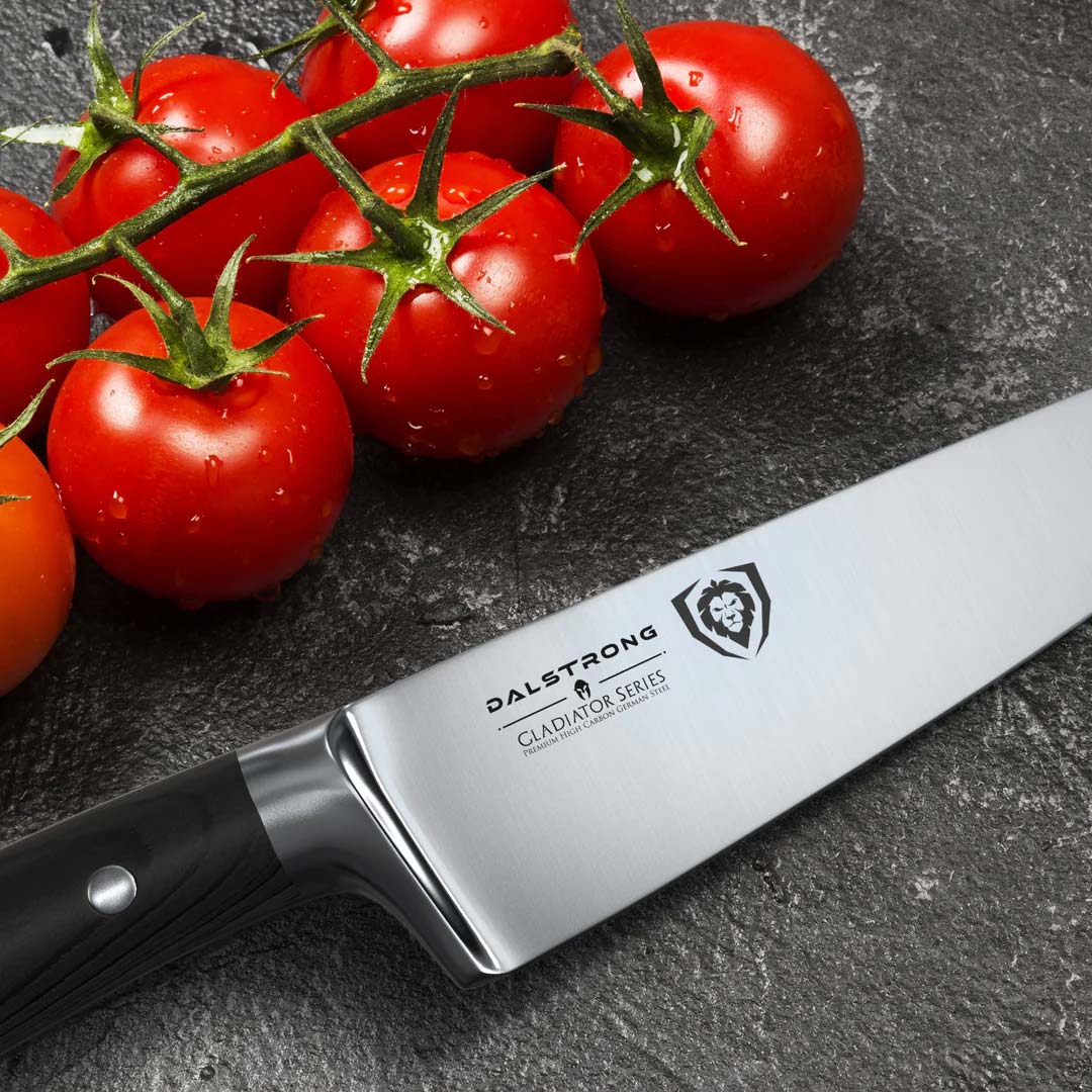 Dalstrong gladiator series 7 inch chef knife with black handle and tomatoes beside it.