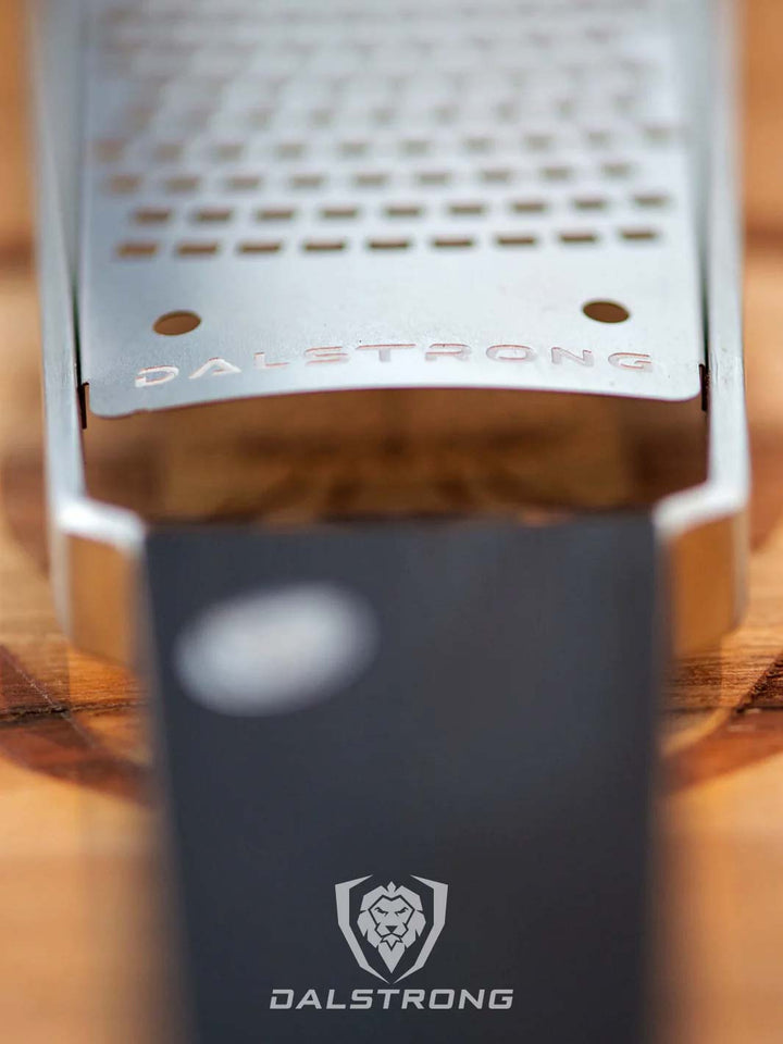 Dalstrong professional coarse wide cheese grater showcasing it's stainless steel grater with dalstrong engraved on it.