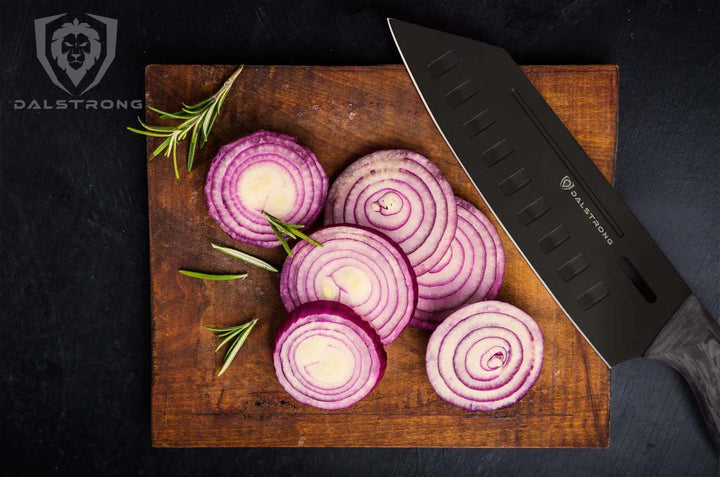 Dalstrong delta wolf series 7 inch santoku knife with slices of onions on a cutting board.