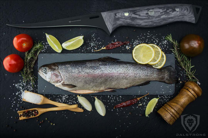 Unboxing the Dalstrong delta wolf series 6 inch fillet knife with black blade and sheath beside a whole fish with lemons.