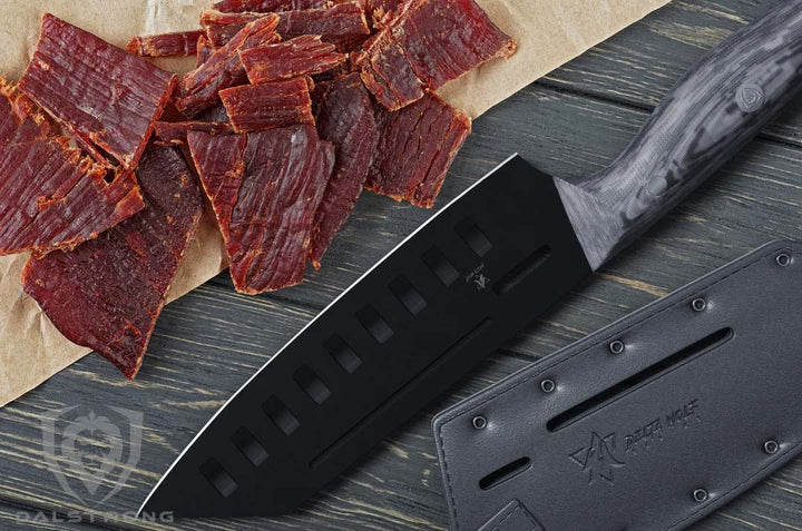 Dalstrong delta wolf series 7 inch santoku knife with thin slices of meat beside it.