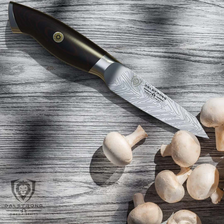 Dalstrong omega series 4 inch paring knife with mushrooms on a wooden table.