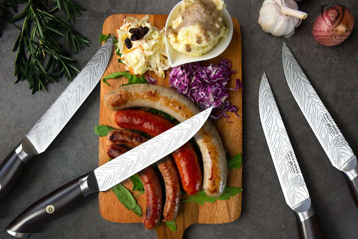 Dalstrong omega series 5 inch steak knife set with four sausages on a cutting board.