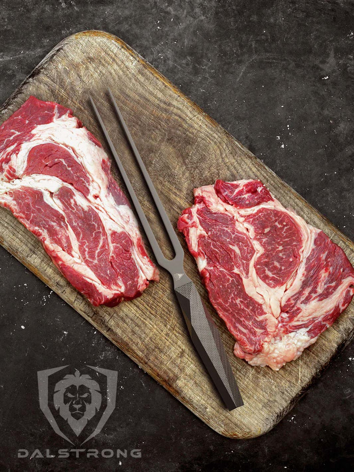 Dalstrong shadow black series 8.5 inch meat fork in the middle of two steaks.
