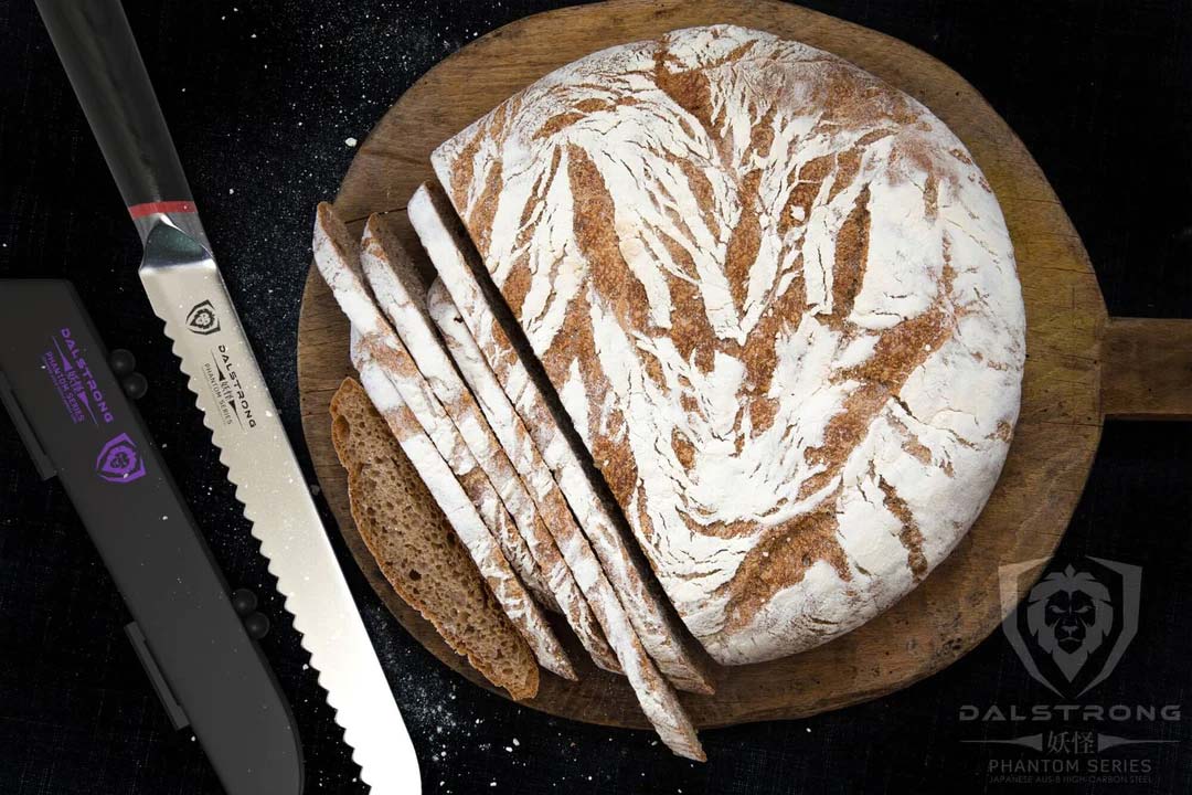 Dalstrong phantom series 9 inch serrated bread knife with pakka wood handle and slices of round bread on a cutting board.