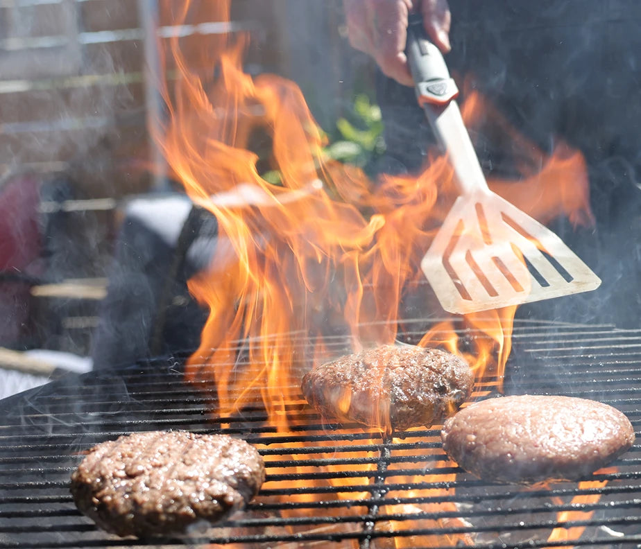 <h6>Handles direct heat, easily.</h6><p>Every component, head to handle, is engineered to hold up to the realities of open-flame cooking. The Titanium Nitride coating, the heat-stable polymers in the KNURLOX™ handle, the corrosion resistance throughout.</p><h6>No backing off the fire.</h6><p>Reach into the flame, lean over the coals, work close to the grates. The spatula takes it.</p>