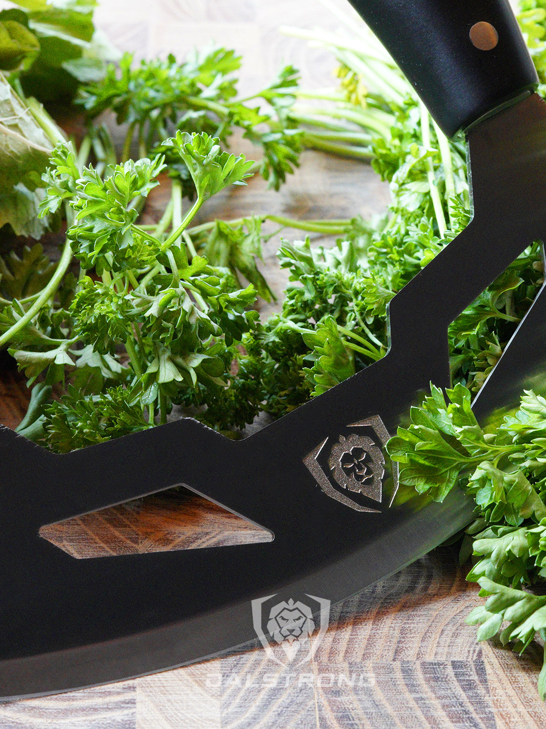 Dalstrong gladiator series 8.5 inch mezzaluna knife with black handle and parsley beside it.