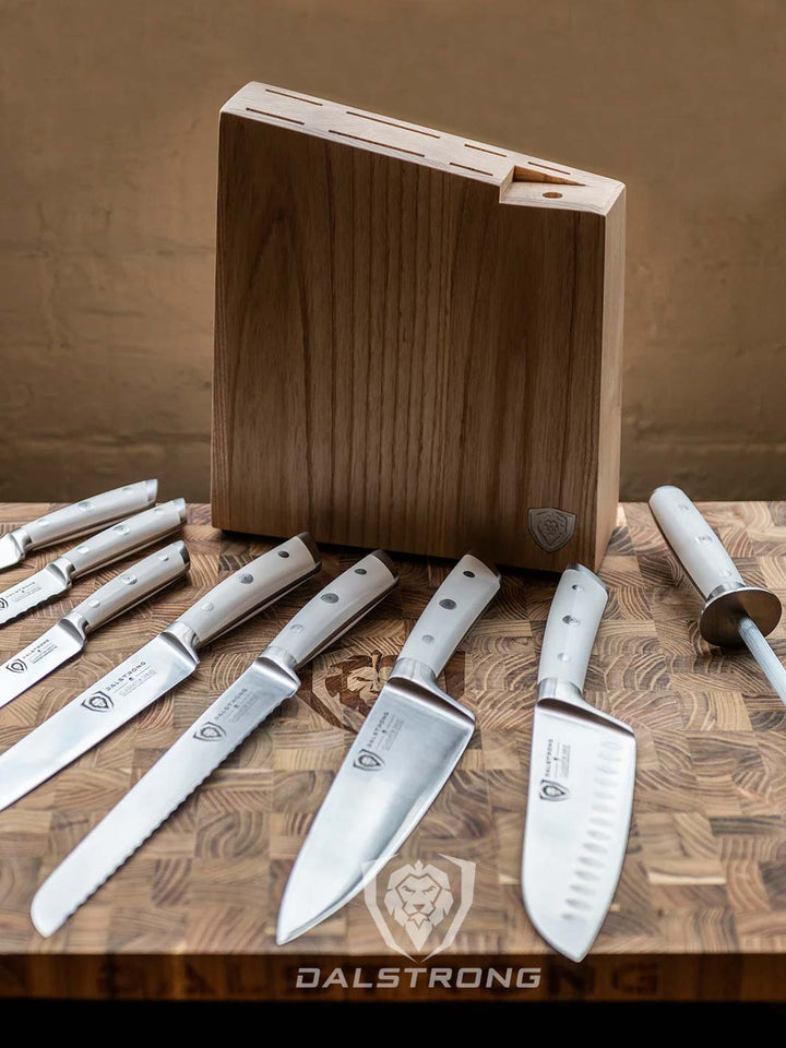 Dalstrong gladiator series 8 piece knife block set with white handles on top of a dalstrong wooden cutting board.