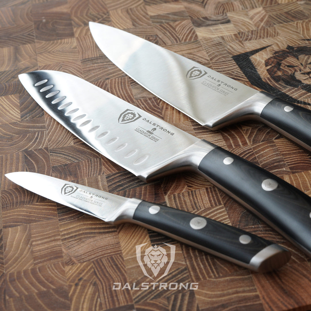 Dalstrong gladiator series 3 piece knife set with black handles on a dalstrong cutting board.
