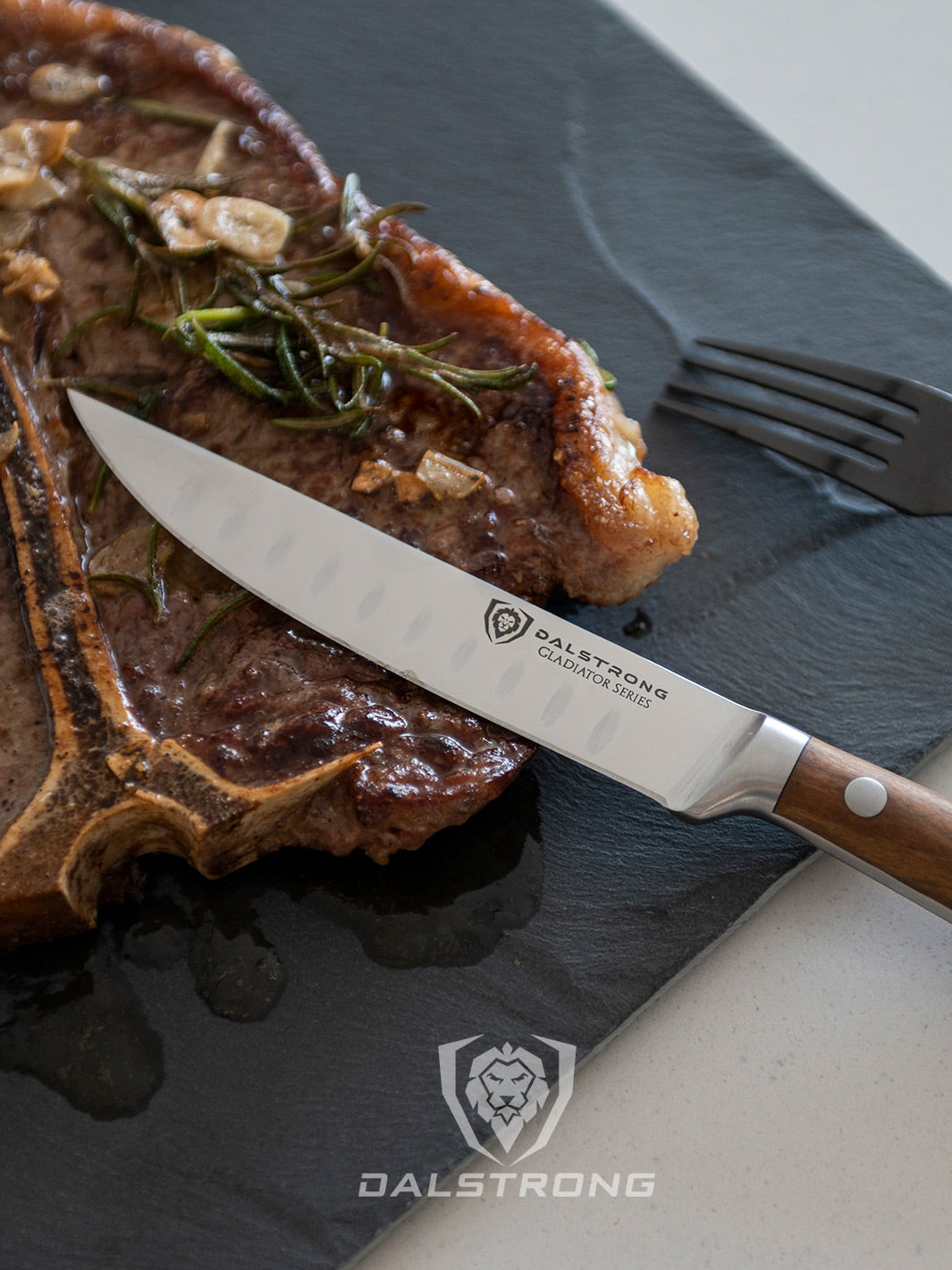 Dalstrong gladiator series 4 piece steak knife set with olive wood handle on top of a t-bone steak.