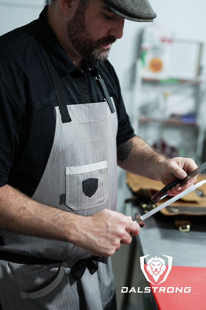 Dalstrong the gandalf professional chef's kitchen apron on a man holding a honing rod.