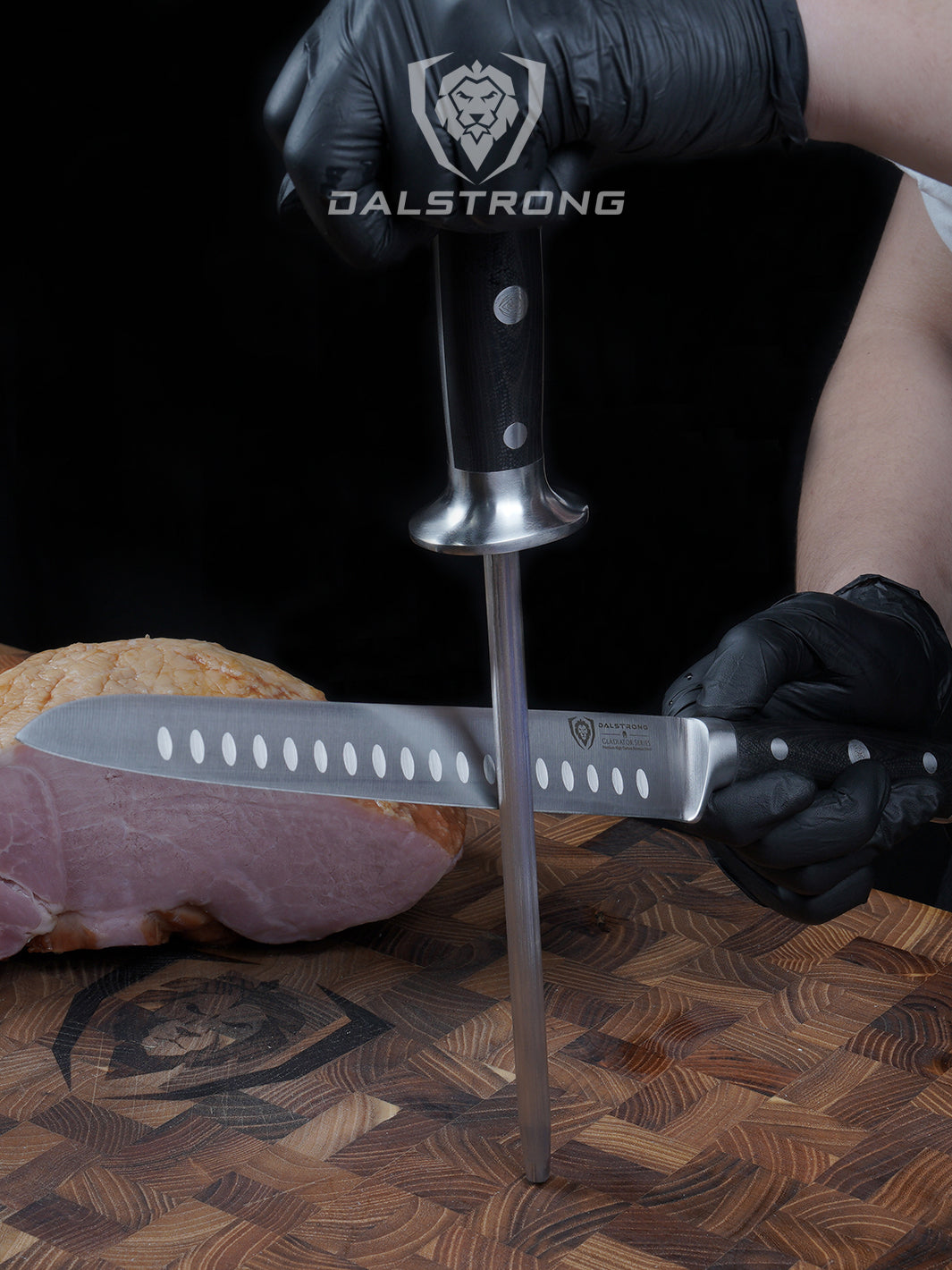 A man's hand with gloves honing the dalstrong gladiator series 9 inch carving knife on top of a dalstrong wooden board.