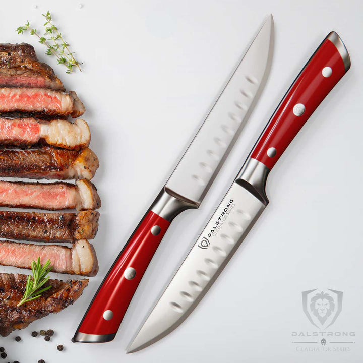 Dalstrong gladiator series steak knife set with red handles beside some slices of steak.