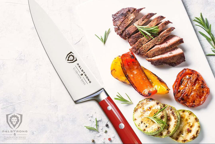 Dalstrong gladiator series 8 inch chef knife with red handle and slices of steak on a white surface.