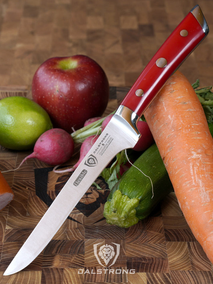 Dalstrong gladiator series 6 inch boning knife with red handle and vegetables beside it.