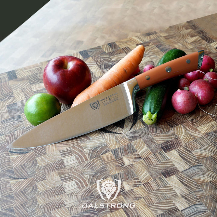 Dalstrong gladiator series 8 inch chef knife with orange handle beside some fruits and vegetables.