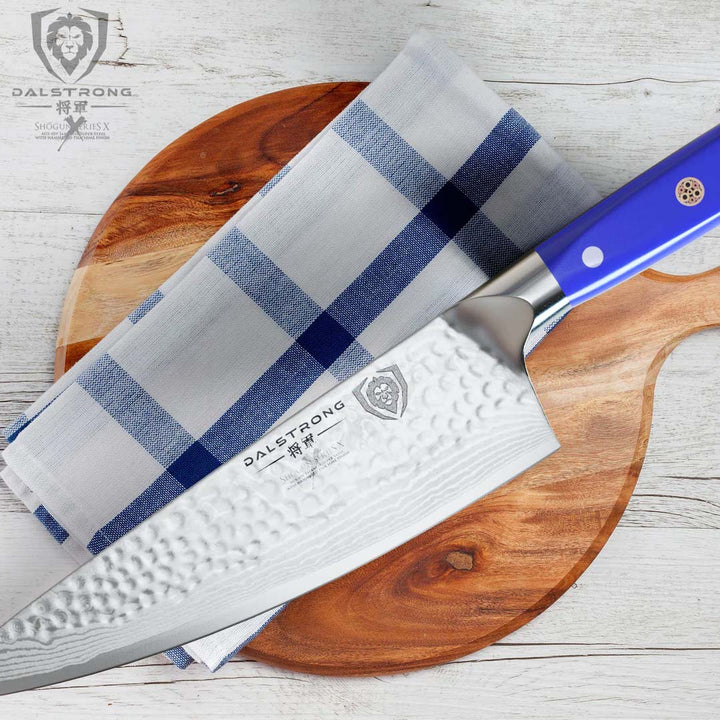 Dalstrong shogun series 8 inch chef knife with blue handle on top of a towel and wooden board.