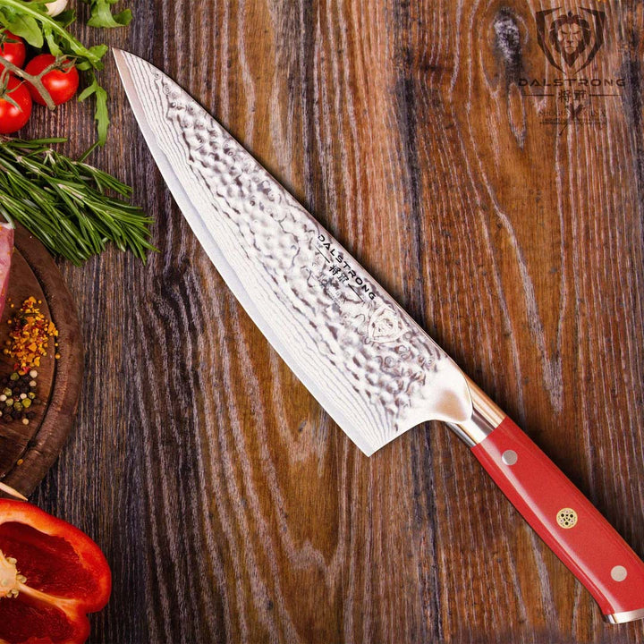 Dalstrong shogun series 8 inch chef knife with red handle in top of a wooden table.