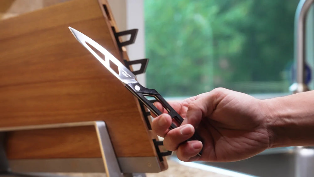 An Arro knife held in a hand by its open-frame handle
