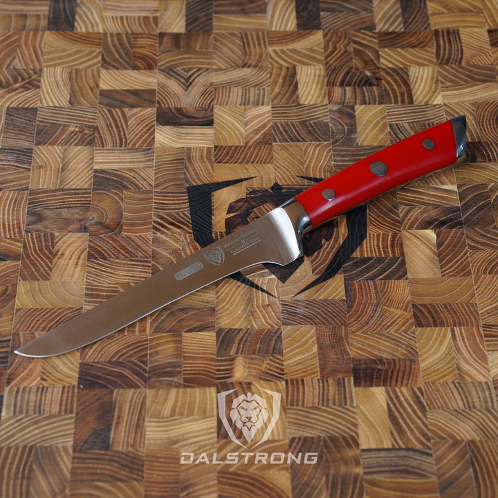 Dalstrong gladiator series 6 inch boning knife with red handle in top of a dalstrong cutting board.