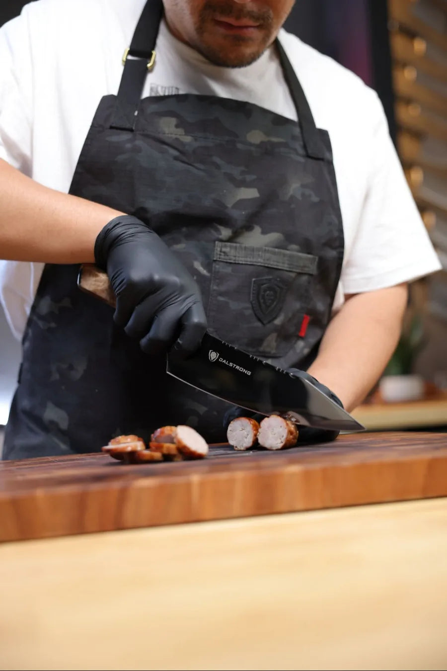Valhalla Ravenstone chef knife from the two-piece set slicing sausage on a cutting board