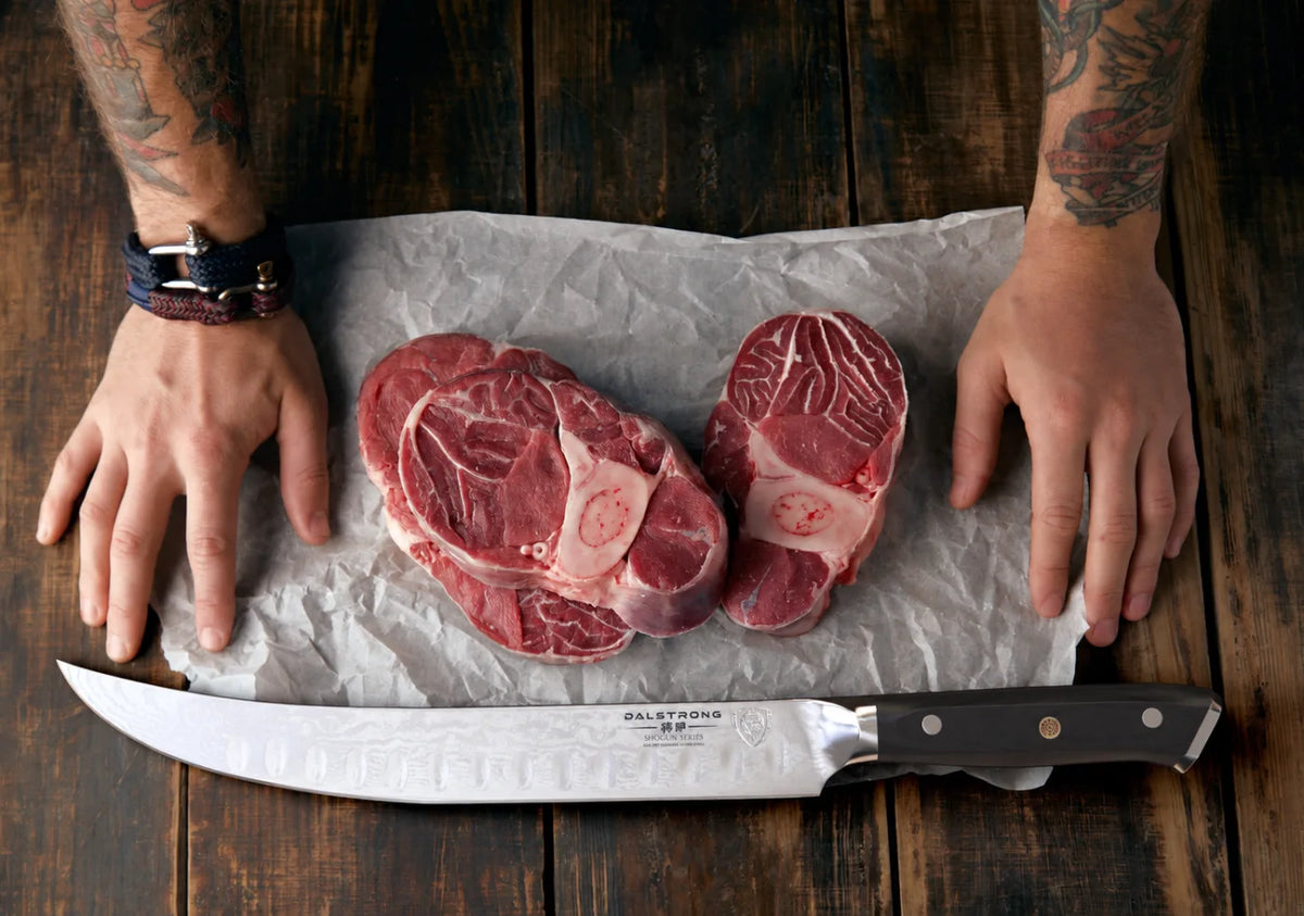 Shogun Series 10-inch cimitar beside neatly prepared cuts of meat on a wooden butcher’s table
