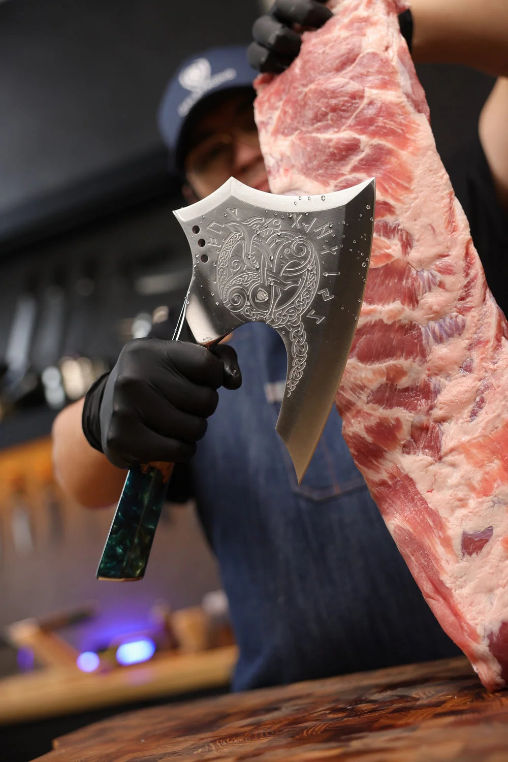 Cook holding the complete Valhalla Meat Axe beside a rack of ribs