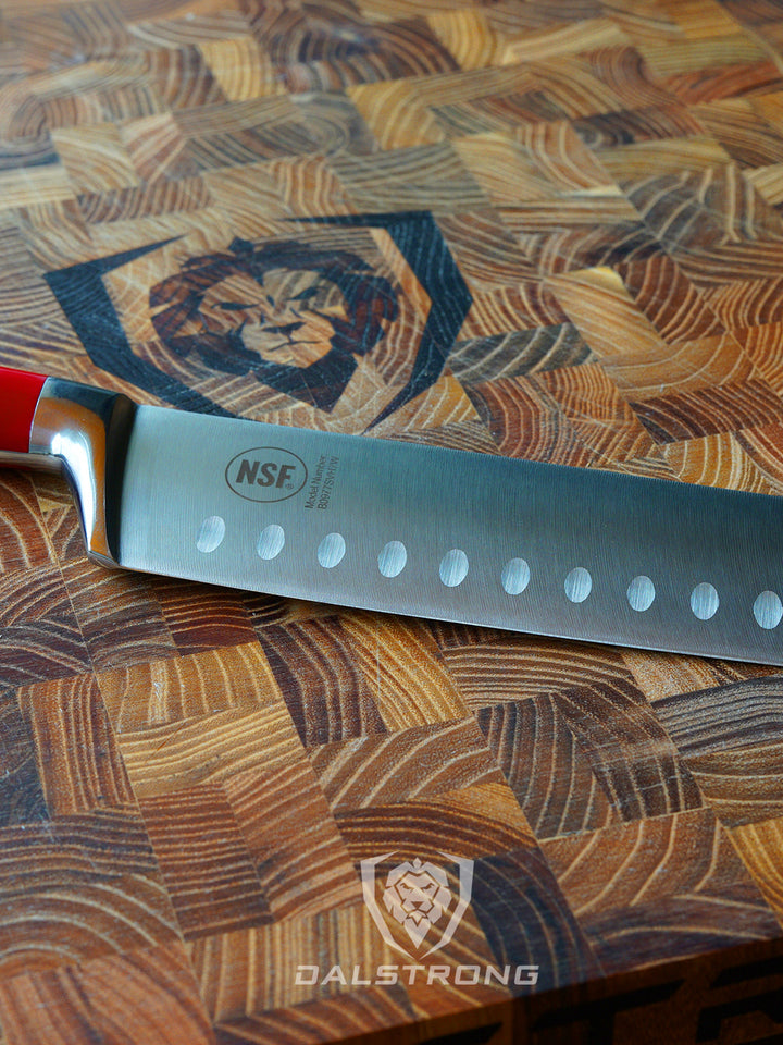 Dasltrong gladiator series 7 inch nakiri knife with red handle on top of a dalstrong cutting board.