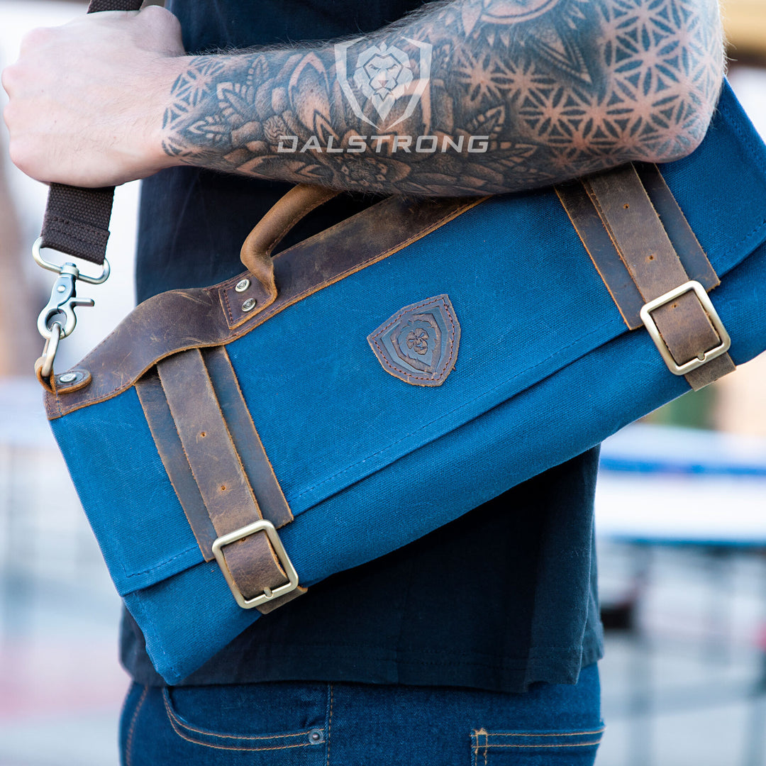 A man with tattoo using the Dalstrong 12oz heavy-duty canvas and leather blue nomad knife roll.