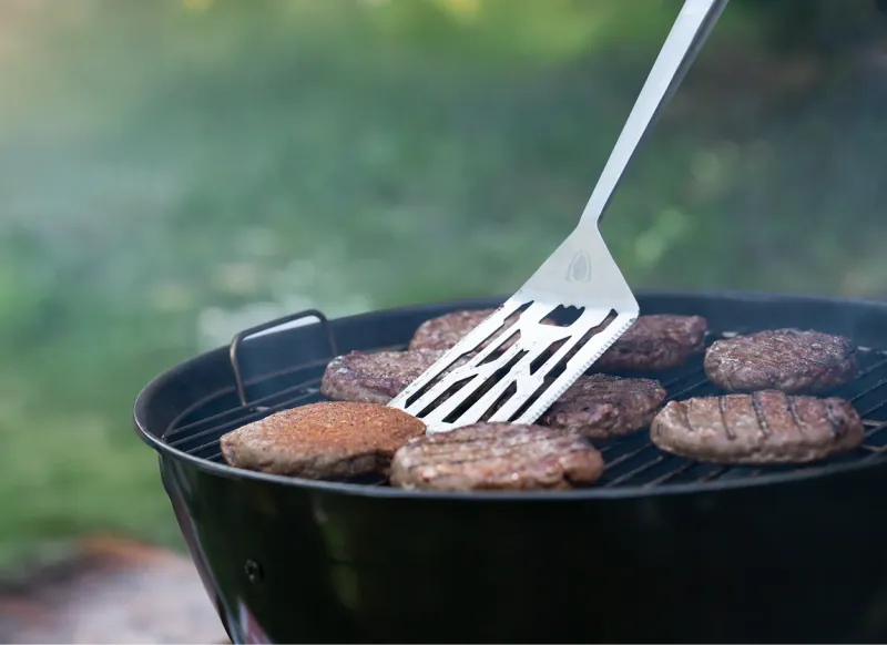 Dalstrong grill tools turning burgers on a barbecue