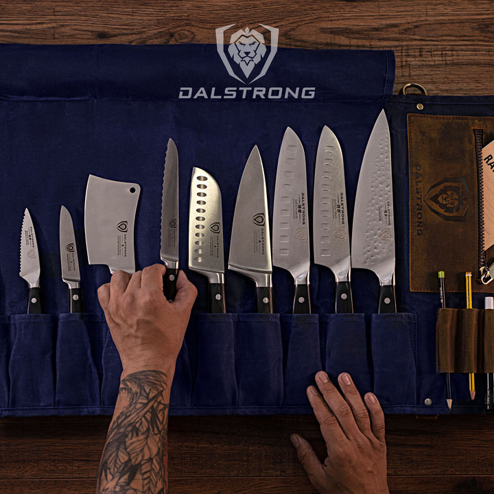 Dalstrong 12oz heavy-duty canvas and leather blue nomad knife roll with knives inside on top of a table.