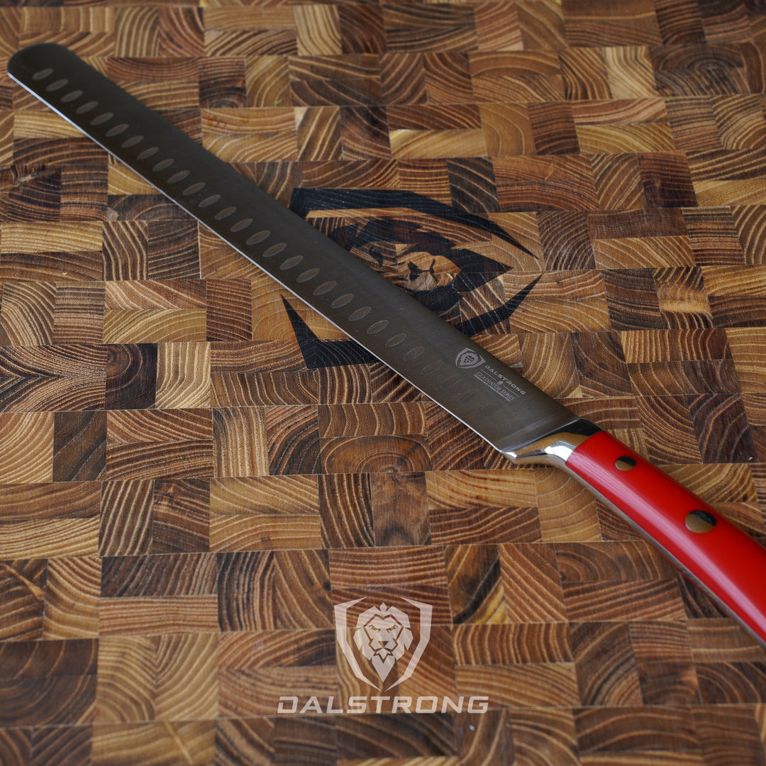 Dalstrong gladiator series 12 inch slicer knife with red handle in top of a dalstrong wooden cutting board.