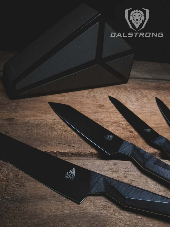 Dalstrong shadow black series 5 piece knife set with block on top of a wooden table.