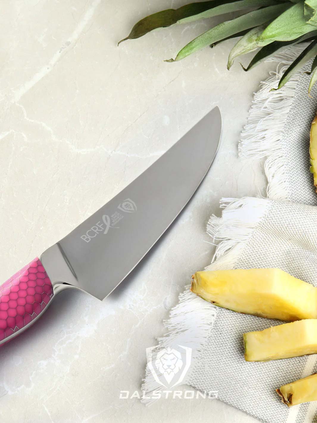 Dalstrong frost fire series 8 inch chef knife with pink handle and slices of pineapple.