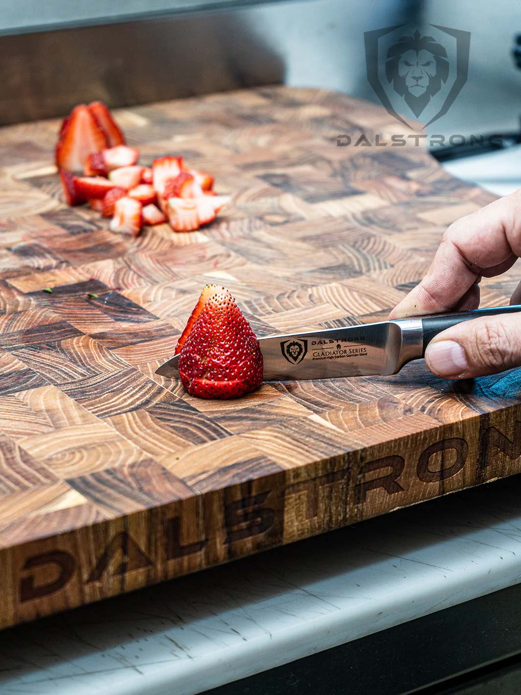 Dalstrong gladiator series 3 piece paring knife set with black handle and slices of strawberry on a dalstrong wooden cutting board.