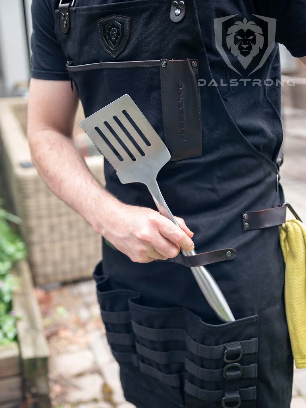 Dalstrong heavy-duty waxed canvas bbq apron beside a spatula.